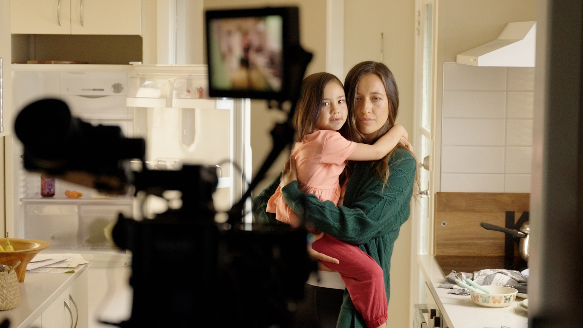 Woman holding her daughter with video camera in front