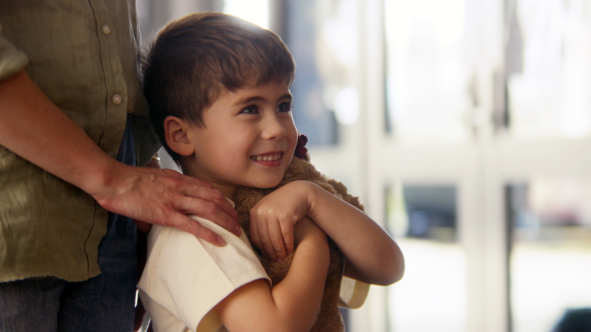 Boy smiling and hugging Koha the bear